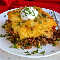 a white plate topped with a casserole covered in meat and veggies