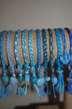 several bracelets hanging from a rope with blue beads and tassels on it