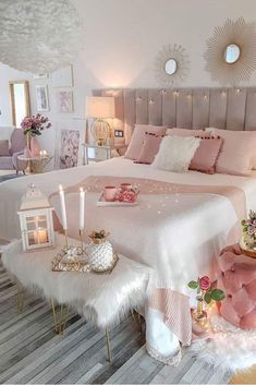 a bedroom decorated in pink and white with candles on the bed