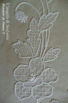 a close up of an embroidered cloth with flowers and leaves on the bottom, in white