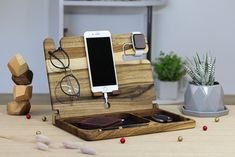 an iphone charging station made out of wood with glasses and cell phone in it on a table