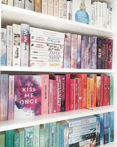 a book shelf filled with lots of books on top of white shelves next to each other