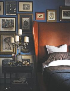 a bed sitting in a bedroom next to a wall with pictures on it and two lamps