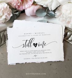 a wedding card with the word still one written on it and flowers in the background