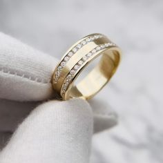 a gold wedding ring with two rows of diamonds on it's side, resting on a white cloth