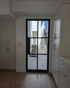 an empty kitchen with white cabinets and black glass doors