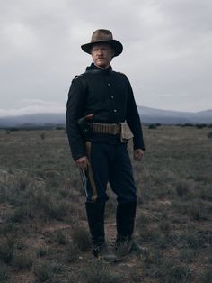 an old man in uniform standing in the middle of a field