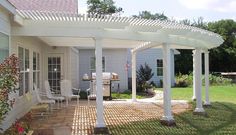 a white pergolated covered patio area next to a house