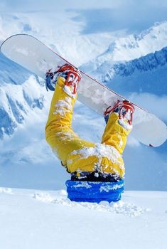 a snowboarder is upside down in the snow with his board on their feet