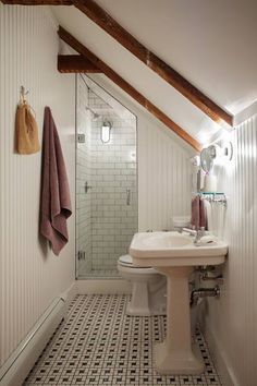 a bathroom with white walls and black and white tile flooring, along with a walk in shower