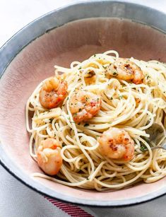 a bowl filled with pasta and shrimp on top of a table