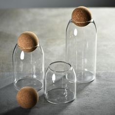 three clear glass jars with cork lids on the top one is empty and the other has a brown cork lid