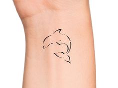 a woman's arm with a small tattoo of a dolphin on it