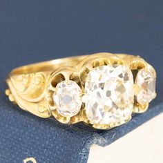 an antique three stone diamond ring on top of a book