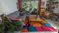 a living room filled with furniture and lots of plants on top of the rugs