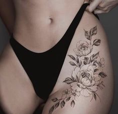 a woman's stomach with flowers and leaves tattooed on the side of her body