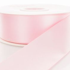 a roll of pink satin ribbon on a white background