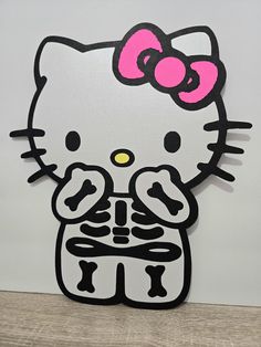 a hello kitty cutout sitting on top of a wooden table next to a white wall