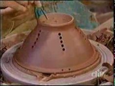 a clay pot with holes in the middle and a spoon sticking out of it's top