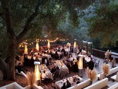 an outdoor dining area is lit up with candles and lights at the end of it