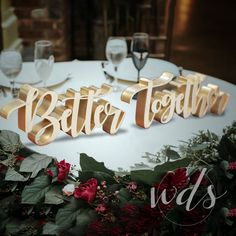 a table topped with flowers and letters that spell out the word better together on top of it