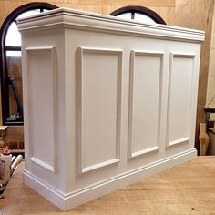 a large white cabinet sitting on top of a wooden table