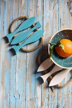 an orange sitting in a bowl next to wooden spoons on top of a table