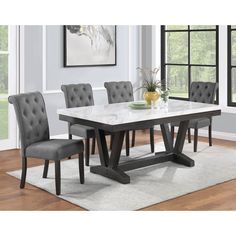 a dining room table with grey chairs and a white rug on the floor in front of it