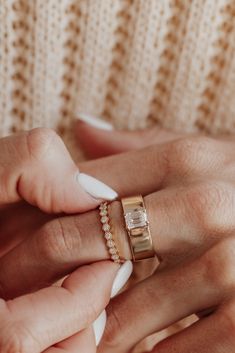 a woman's hands with two different rings on her fingers and one is holding the other