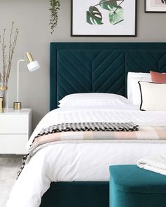 a bedroom with a green headboard and white bedding, two framed pictures on the wall