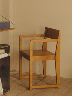 a wooden chair sitting next to a desk with a book on it's side