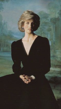 a woman sitting in front of a painting wearing a black dress and holding her hands together