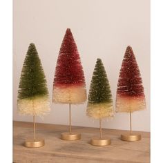 three small trees with different colors and sizes on top of each other in gold bases