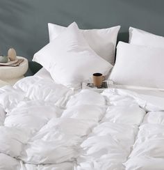 an unmade bed with white comforters and pillows