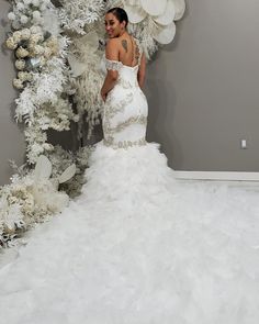 a woman in a white wedding dress standing next to a christmas tree