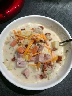 a bowl of soup with ham, potatoes and carrots in it on a table