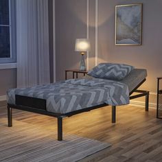 a bed sitting on top of a hard wood floor next to a night stand and lamp