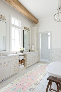 a large bathroom with white cabinets and marble counter tops, along with a pink rug on the floor