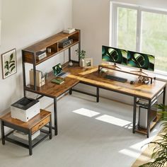 a computer desk with two computers on top of it in front of a large window