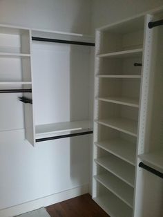 an empty walk in closet with white shelving and black piping on the shelves