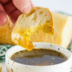 a person dipping something into a bowl of soup