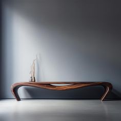 a wooden table sitting on top of a white floor next to a vase filled with flowers