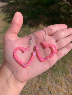 "Each pair of resin earrings are handmade to order, therefore no two pairs are identical! However, I try to get as close as possible :) Made with nickel free, hypoallergenic, sterling silver plated fish hooks.  Heart width and height is approximately 1.5\"x1.5\", and is made with epoxy resin and light pink chunky holographic mix glitter 💖 Glows in blacklight!   Thanks for visiting my shop! ✨" Pink Heart-shaped Resin Jewelry, Pink Resin Heart Earrings For Gift, Pink Resin Heart Earrings As Gift, Pink Heart Resin Earrings, Resin Heart Earrings For Gifts, Pink Resin Jewelry With Heart Charm, Cute Resin Heart Earrings For Valentine's Day, Heart Shaped Resin Jewelry For Party, Pink Resin Heart Earrings Handmade