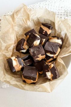 chocolate covered marshmallows in a bowl on a white tablecloth with paper