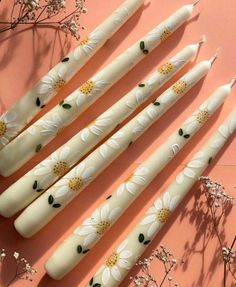 six white and gold flowered candles sitting on top of a pink surface