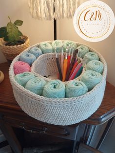 a basket filled with yarn and crochet needles on top of a wooden table