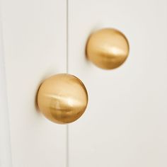 two gold knobs on the side of a white cabinet