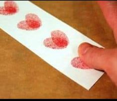 someone is making hearts out of paper on a piece of white paper with red ink