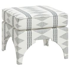 a white and grey ottoman with stripes on the bottom, sitting on top of it