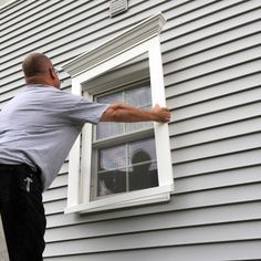 a man is painting the outside of a house with white paint on it's windows